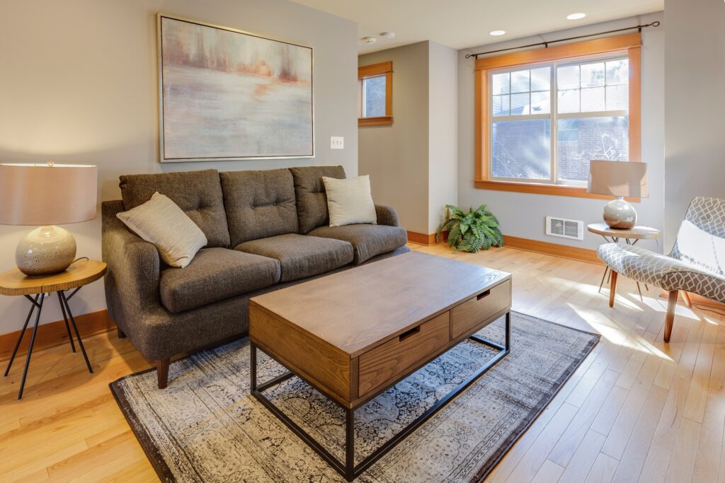 Foto de uma sala de estar com ambiente claro, um sofá marrom e um belo tapete